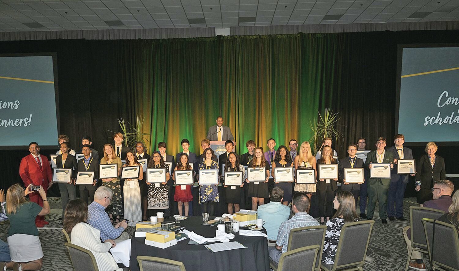 Pictured are the 2023 scholarship winners holding their framed certificates with Juan Calix, Agent State Farm (left); Dr. Paul Burns, Chancellor Florida Department of Education behind the podium; and Cindy O’Connell, Director Florida Prepaid College Savings Plans (right).